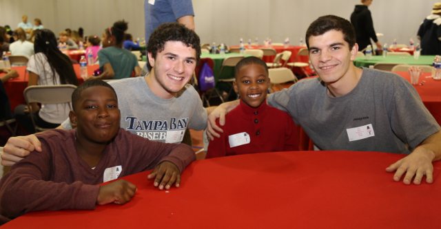 (from the left) Chester Brave Nafis, Henderson Guide Zach Roberts, Chester Brave Brean and Henderson Guide Kyle Hicks enjoy dinner at last year's ACAC Christmas Pool Party. Kyle has also been Brean's Camp Counselor for the past four summers!